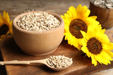 Photo of Raw peeled sunflower seeds and flowers on wooden board