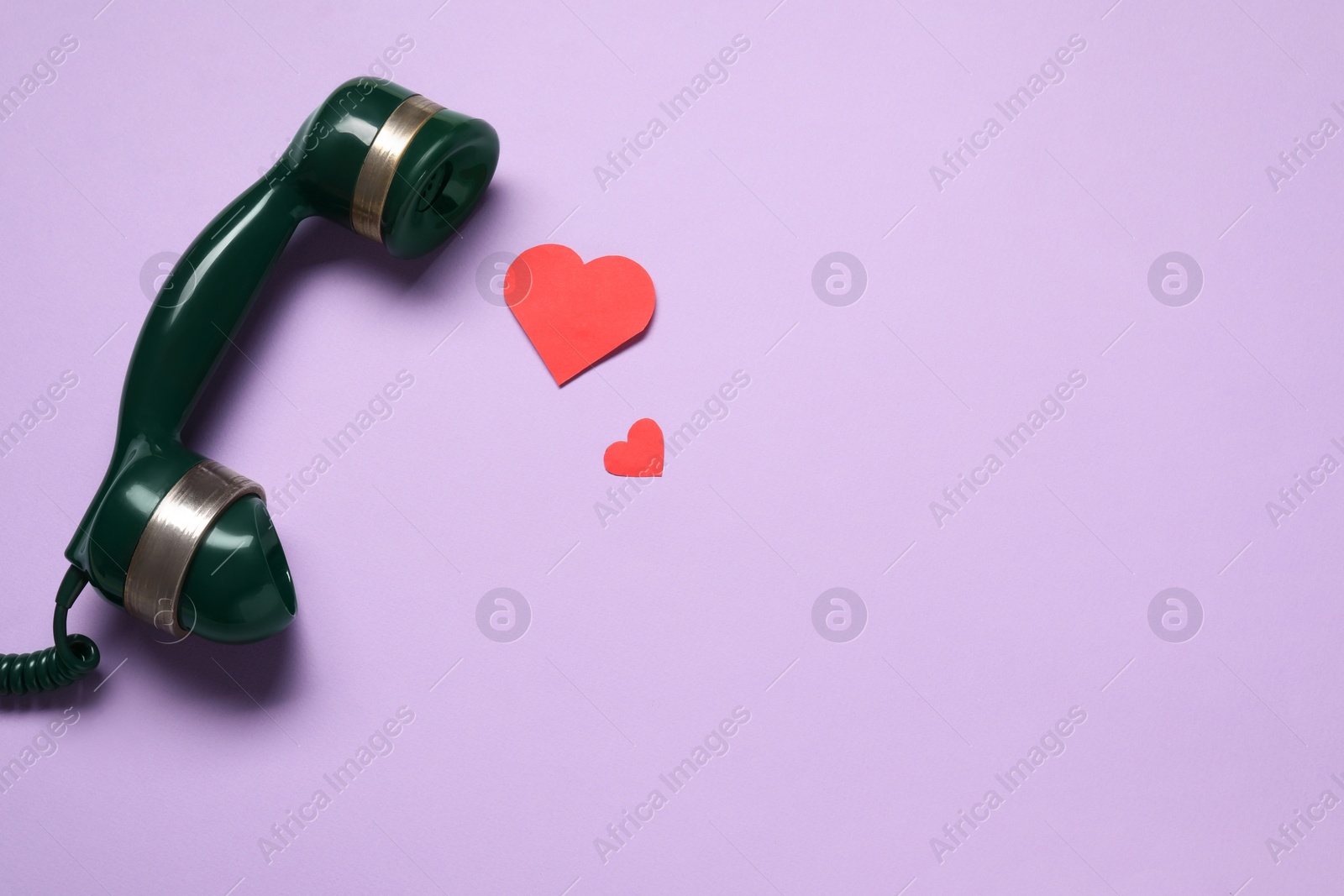 Photo of Long-distance relationship concept. Telephone receiver and paper hearts on violet background, flat lay with space for text