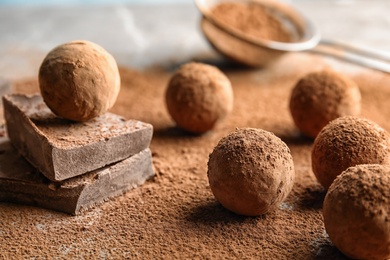 Photo of Sweet raw chocolate truffles powdered with cocoa on table