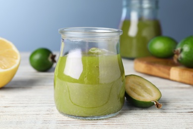 Photo of Feijoa jam and fresh fruit on white wooden table, closeup