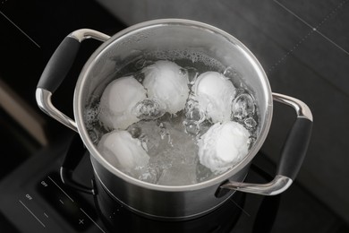 Photo of Chicken eggs boiling in pot on electric stove, above view
