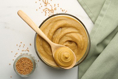 Tasty mustard sauce and dry seeds on white marble table, flat lay