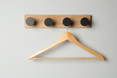 Photo of Rack with empty wooden clothes hanger on white wall