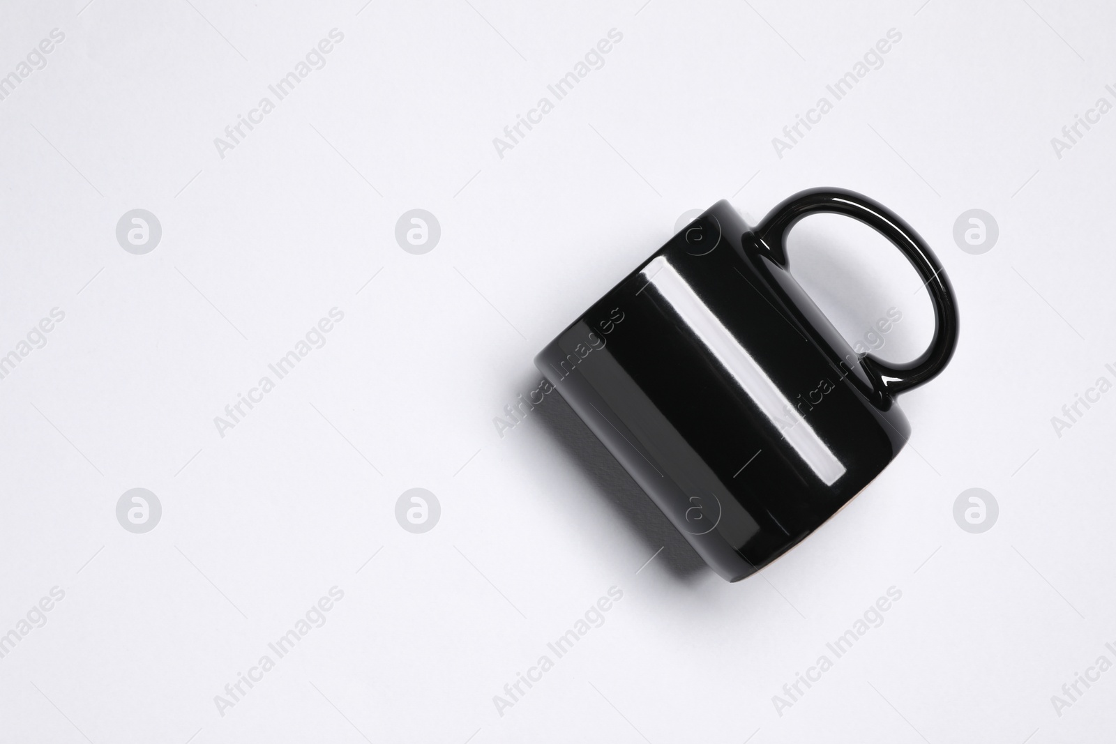 Black ceramic mug on light grey background, top view. Space for text Photo of Black ceramic mug on light grey background, top view. Space for text