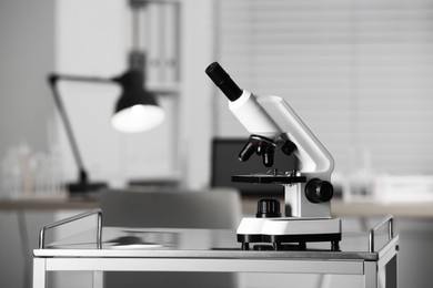 Photo of Modern medical microscope on metal table in laboratory, space for text