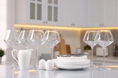 Photo of Set of clean dishware, glasses and cutlery on table in kitchen