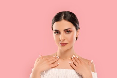Photo of Beautiful woman with elegant jewelry on pink background, space for text