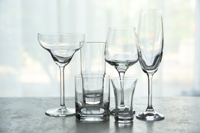 Photo of Different elegant empty glasses on grey table indoors