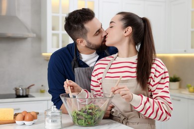 Lovely couple kissing while cooking in kitchen