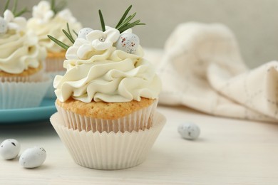 Photo of Tasty Easter cupcakes with vanilla cream on light wooden table