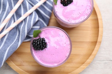 Photo of Delicious blackberry smoothie in glasses on white wooden table, top view