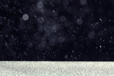 Photo of Glitter on table against dark background. Bokeh effect