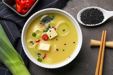 Photo of Bowl of delicious miso soup with tofu served on grey table, flat lay