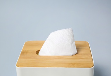 Photo of Holder with paper tissues on light grey background, closeup