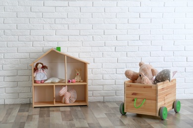 Photo of Wooden storage with toys near white brick wall in baby room interior
