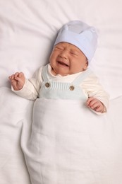 Photo of Newborn baby lying on white blanket, top view