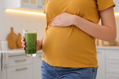 Photo of Young pregnant woman with smoothie in kitchen, closeup. Healthy eating