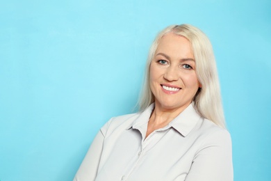 Photo of Portrait of mature woman with beautiful face on light blue background. Space for text