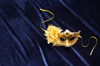 Photo of Theater arts. Golden venetian carnival mask on blue fabric, top view. Space for text