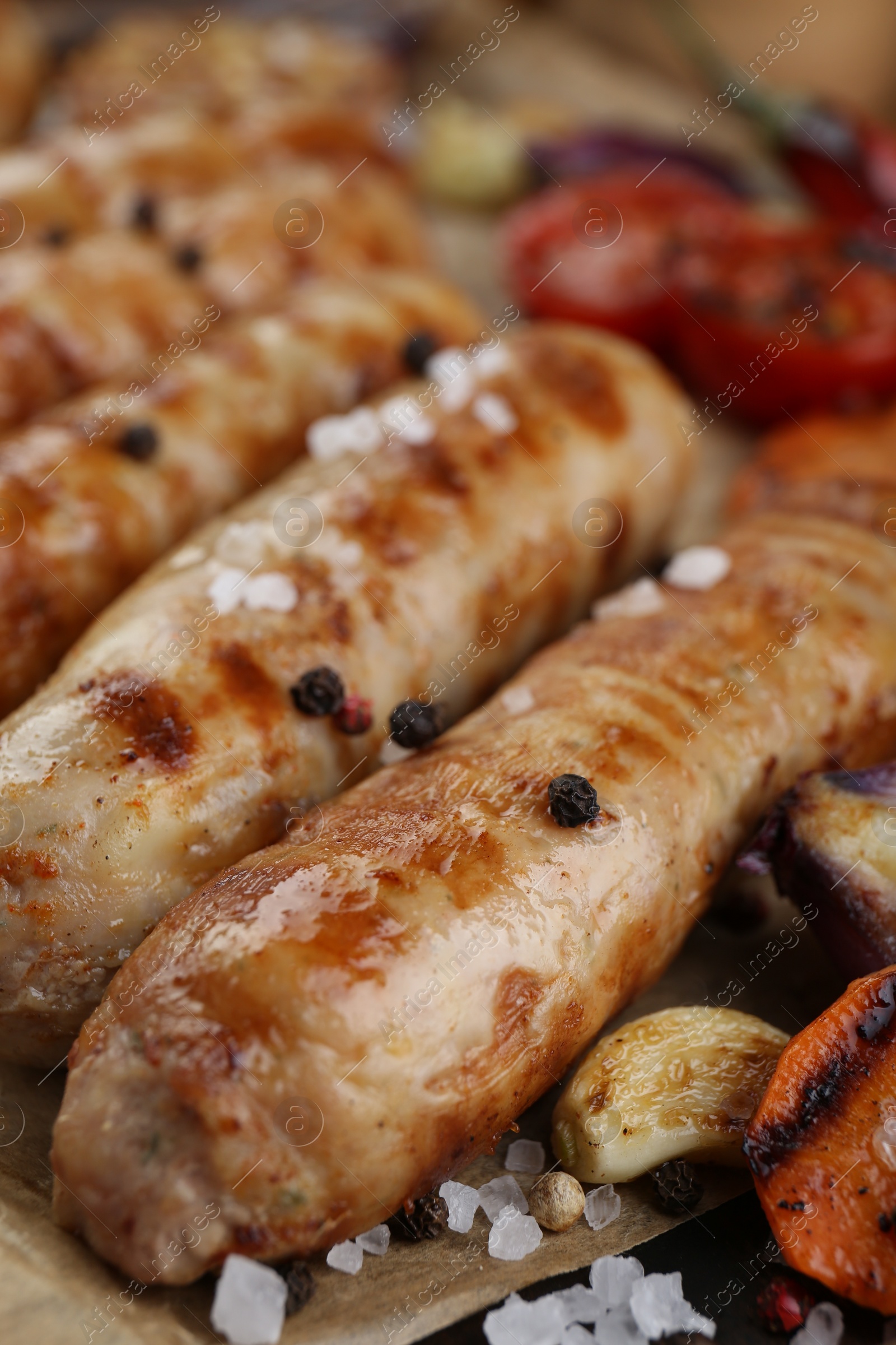 Photo of Tasty grilled sausages on wooden board, closeup