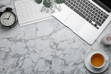 Photo of Flat lay composition with laptop and cup of tea on white marble table. Space for text