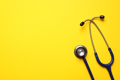 Photo of Stethoscope on yellow background, top view. Space for text