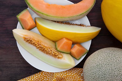 Photo of Whole and cut ripe melons on wooden table, flat lay