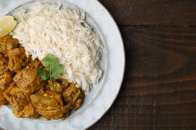 Photo of Delicious chicken curry with rice on wooden table, top view