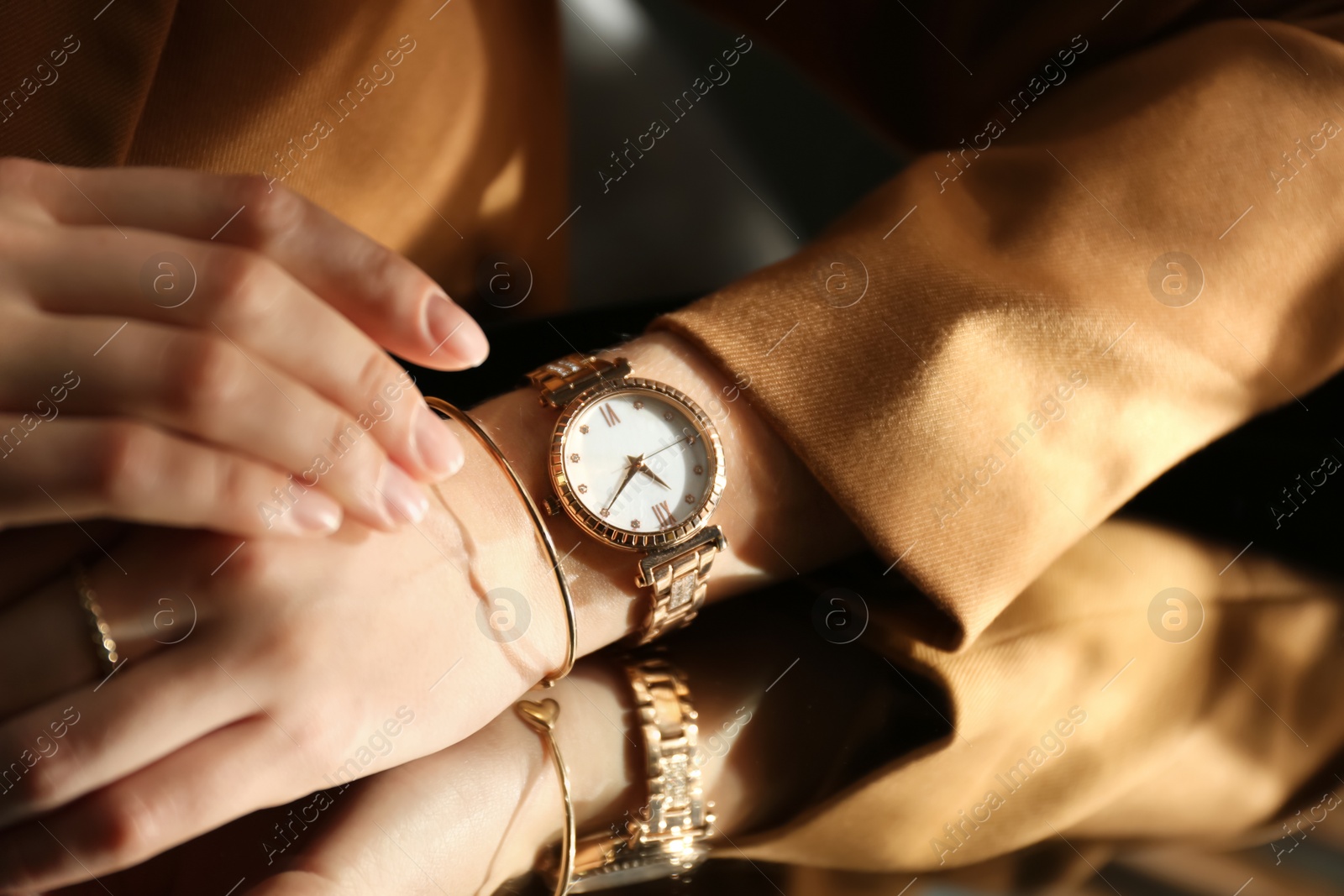 Photo of Woman wearing luxury wristwatch near mirror, closeup