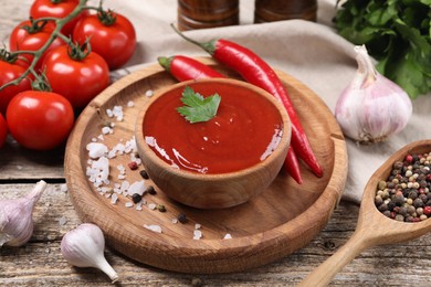 Photo of Delicious ketchup in bowl, products and spices on wooden table, closeup. Tomato sauce