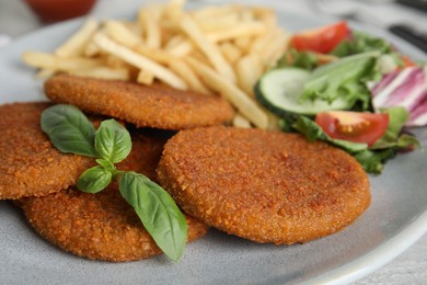 Photo of Delicious fried breaded cutlets with garnish on table, closeup