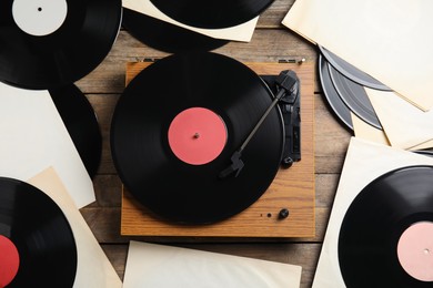 Photo of Modern player and vinyl records on wooden background, flat lay