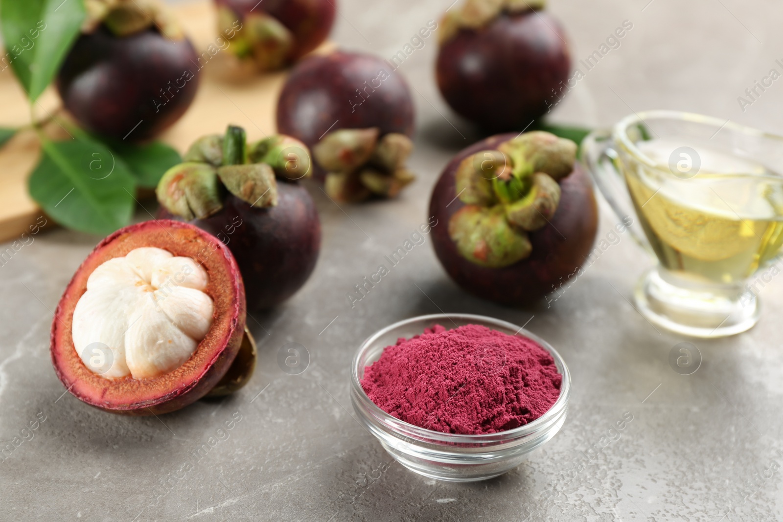 Photo of Purple mangosteen powder and fruits on grey marble table