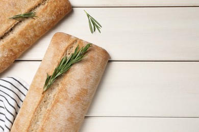 Photo of Delicious ciabattas with rosemary on beige wooden table, flat lay. Space for text