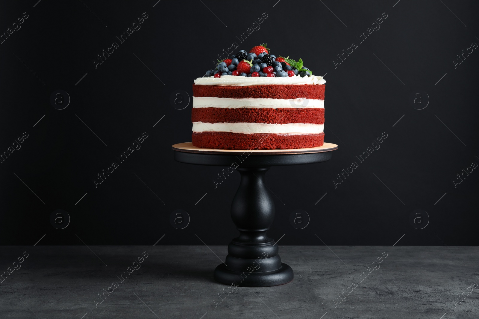 Photo of Stand with delicious homemade red velvet cake on black background