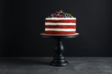 Photo of Stand with delicious homemade red velvet cake on black background