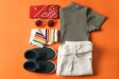 Photo of Stylish child clothes, shoes and accessories on orange background, flat lay