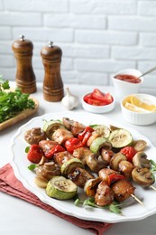 Photo of Delicious shish kebabs with vegetables and microgreens served on table, closeup