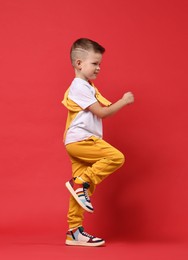 Photo of Happy little boy dancing on red background