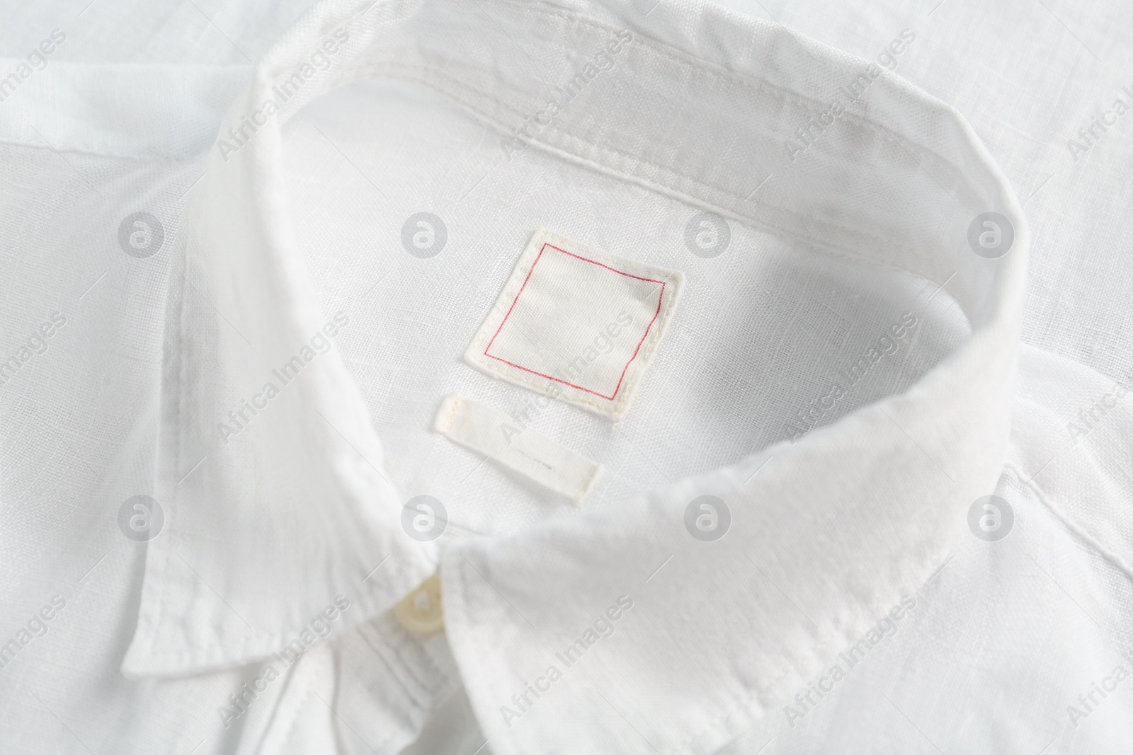 Photo of Blank clothing labels on white shirt, closeup
