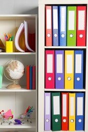 Colorful binder office folders and other stationery on shelving unit