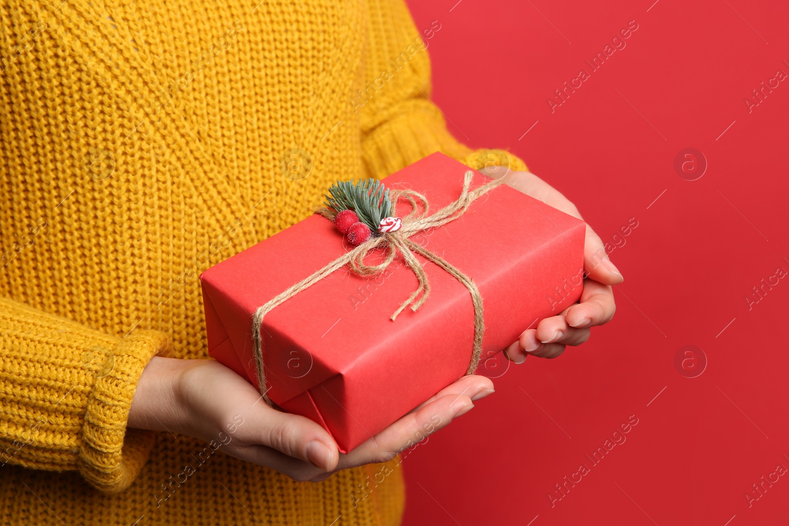 Woman holding Christmas gift box on red background, closeup Photo of Woman holding Christmas gift box on red background, closeup