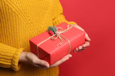Photo of Woman holding Christmas gift box on red background, closeup