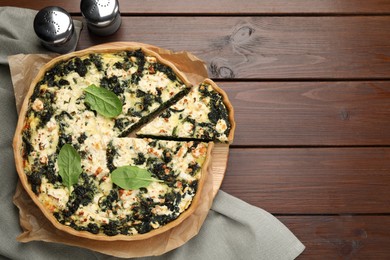 Photo of Delicious homemade spinach quiche on wooden table, flat lay. Space for text