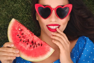 Photo of Beautiful young woman with watermelon on green grass outdoors, top view