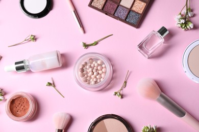 Flat lay composition with different makeup products and beautiful spring flowers on pink background