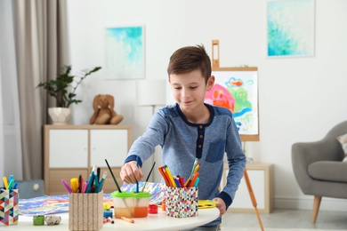 Photo of Little child painting picture at table indoors