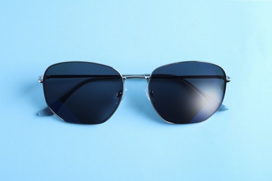 Photo of Stylish sunglasses on light blue background, top view