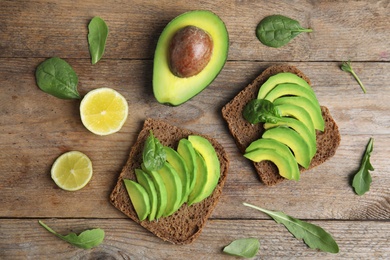 Photo of Flat lay composition with avocado toasts on wooden table