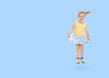 Image of Cute girl jumping on light blue background, space for text